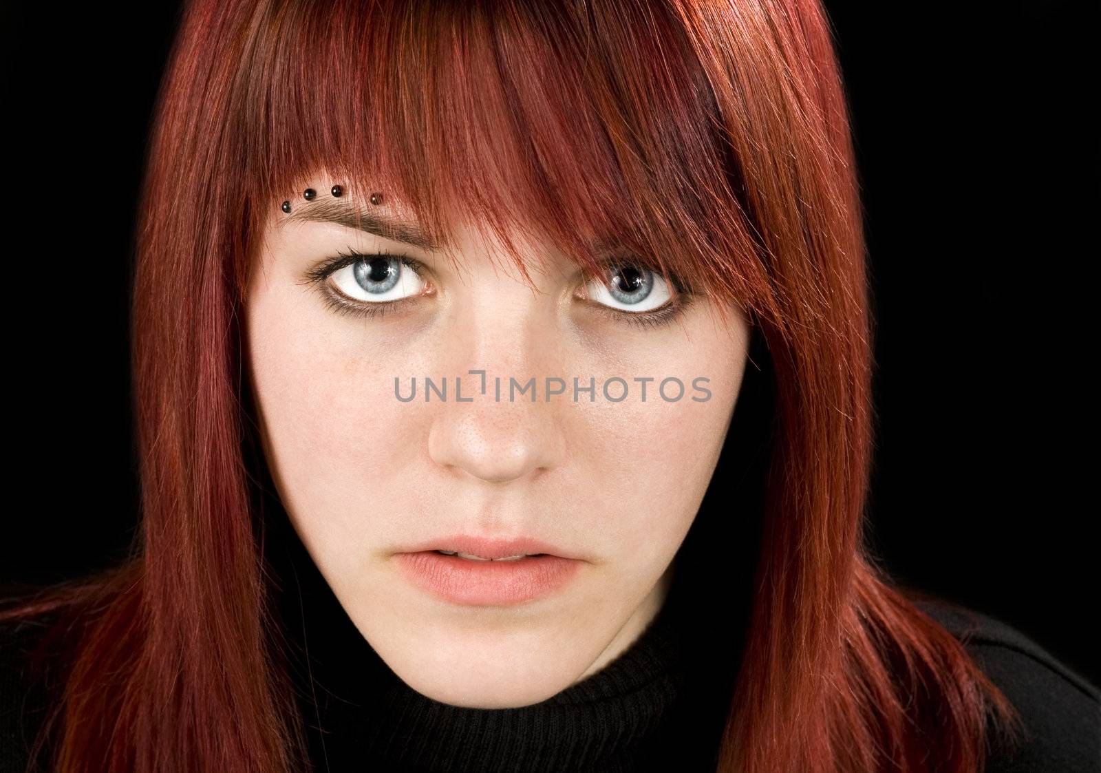 Simple frontal shot of a beautiful pierced redhead girl staring at the camera.

Studio shot.