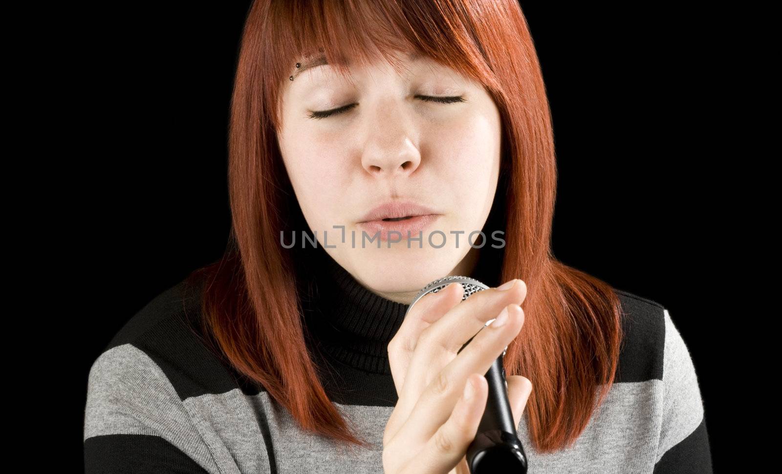Redhead girl singing karaoke with a microphone. Sweet face.

Studio shot.