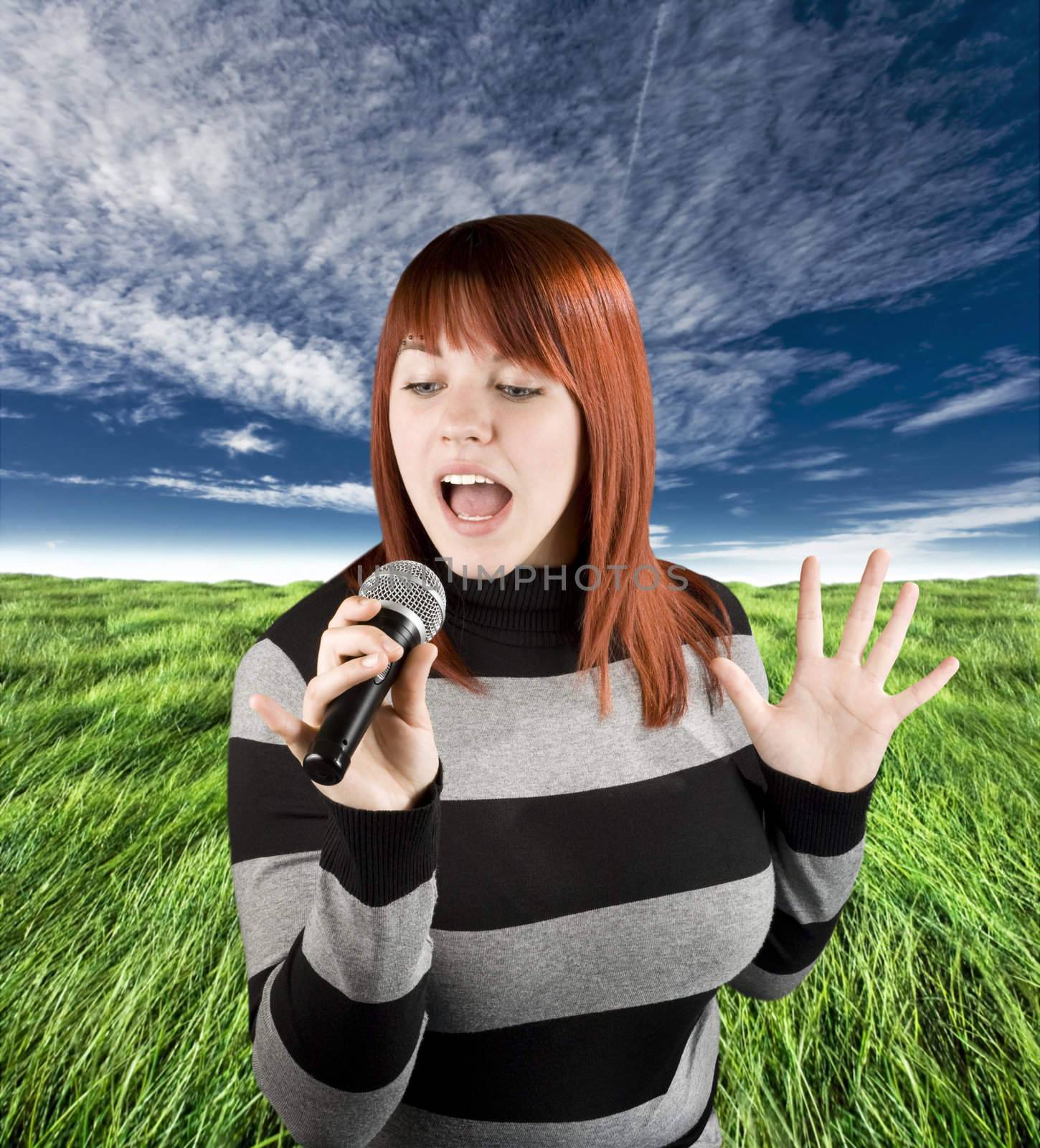 Happy beautiful redhead girl singing on a microphone, karaoke.

Studio shot.