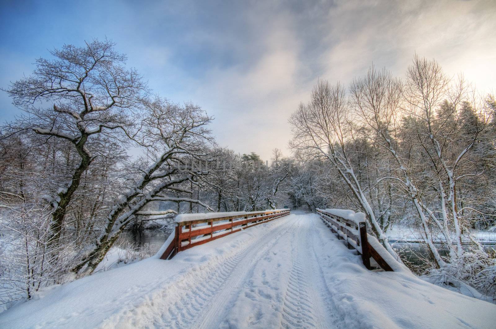 Bridge in winter forest during sunset, lots of snow