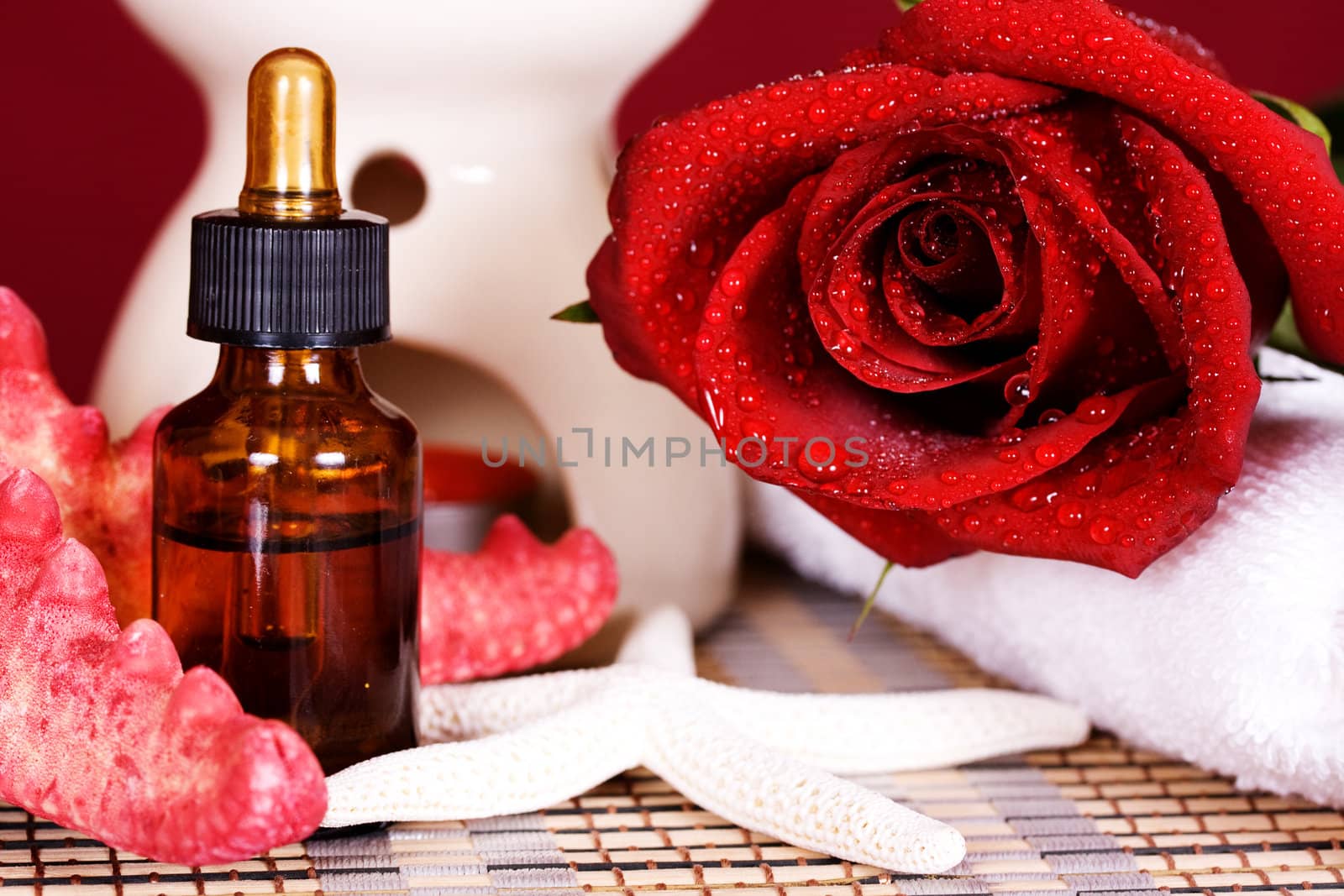 Essential oil and red rose a burning candle