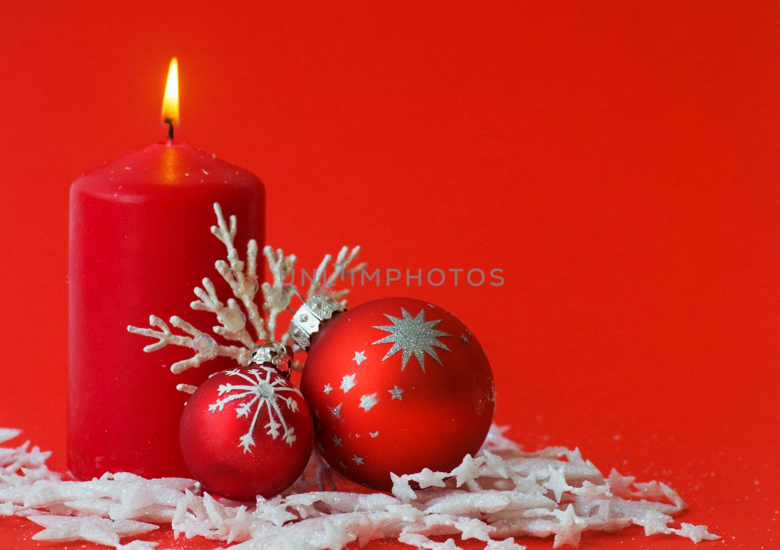 Christmas decoration with candle, balls and ornaments on red background