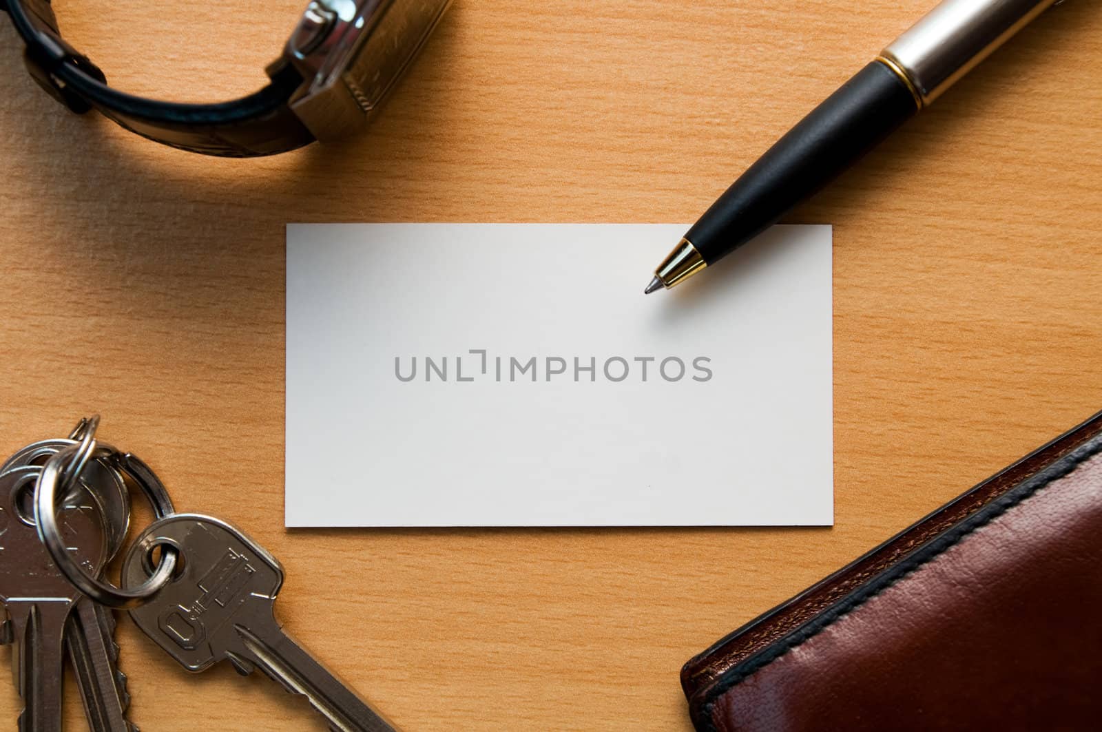 Blank white card in a workplace with business tools - wallet, watch, pen, keys.