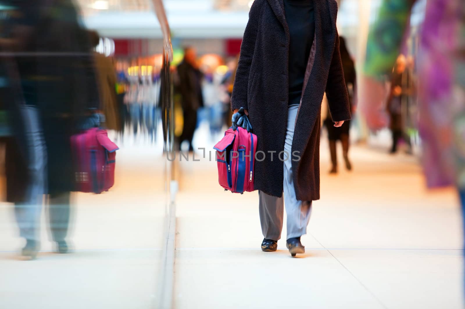People in rush in a modern shopping mall. Close up and reflection of a woman walking