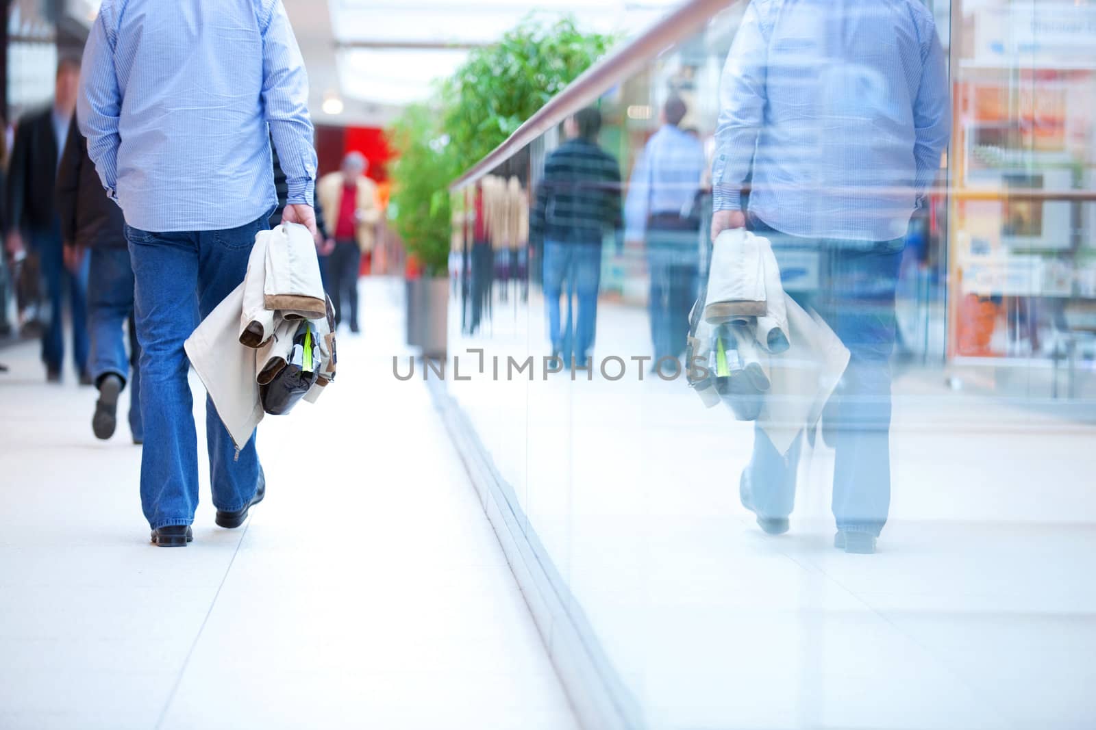 People in rush in a modern shopping mall. Close up and reflection of a man walking