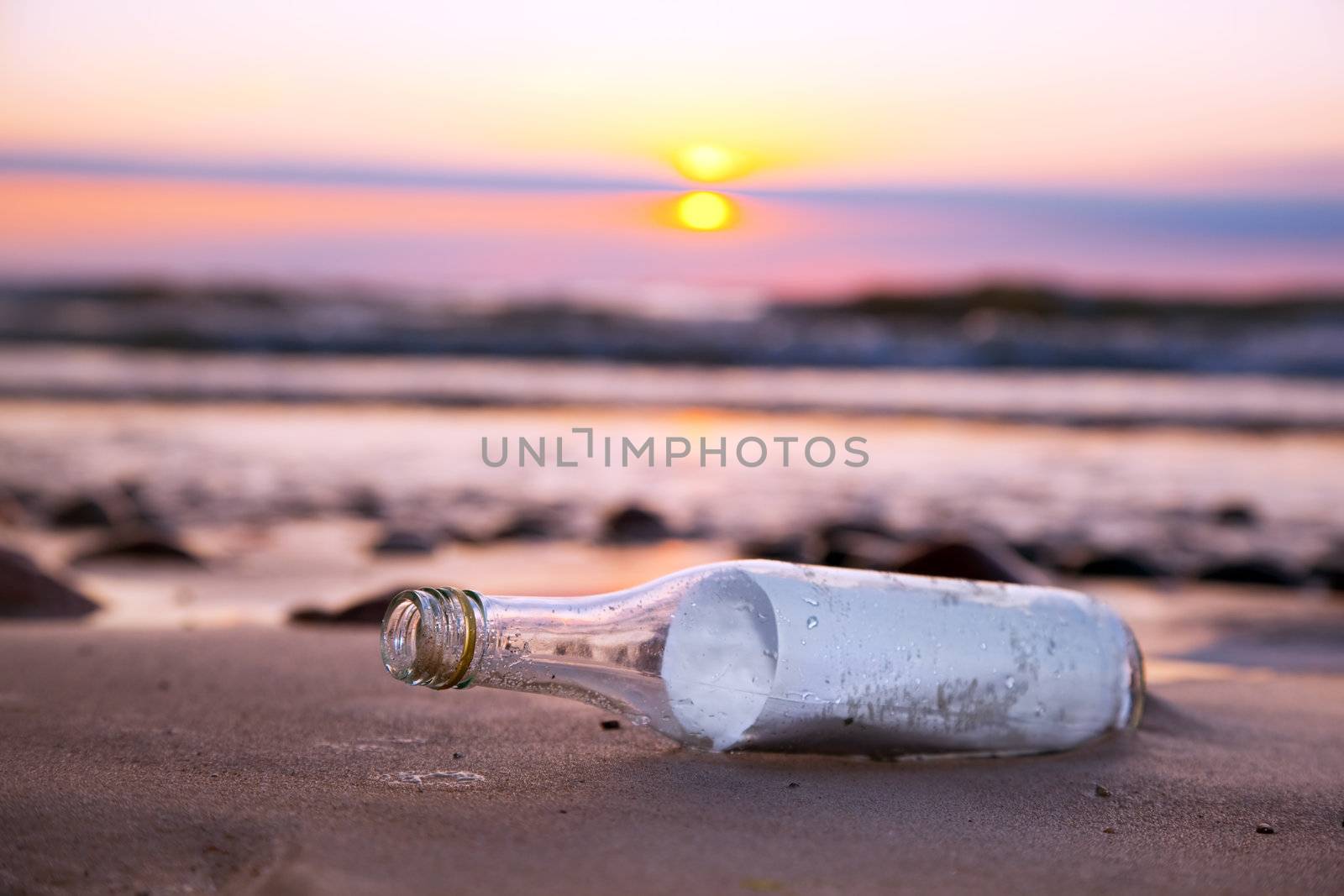 Message in the bottle on the beach at sunset
