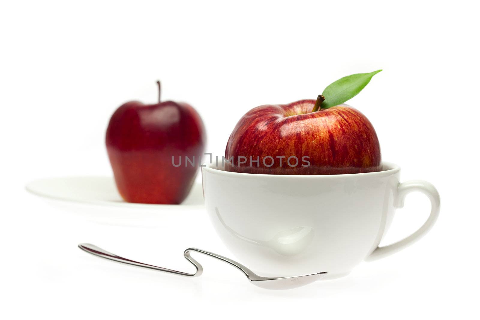 apple in a cup and spoon isolated on white by jannyjus
