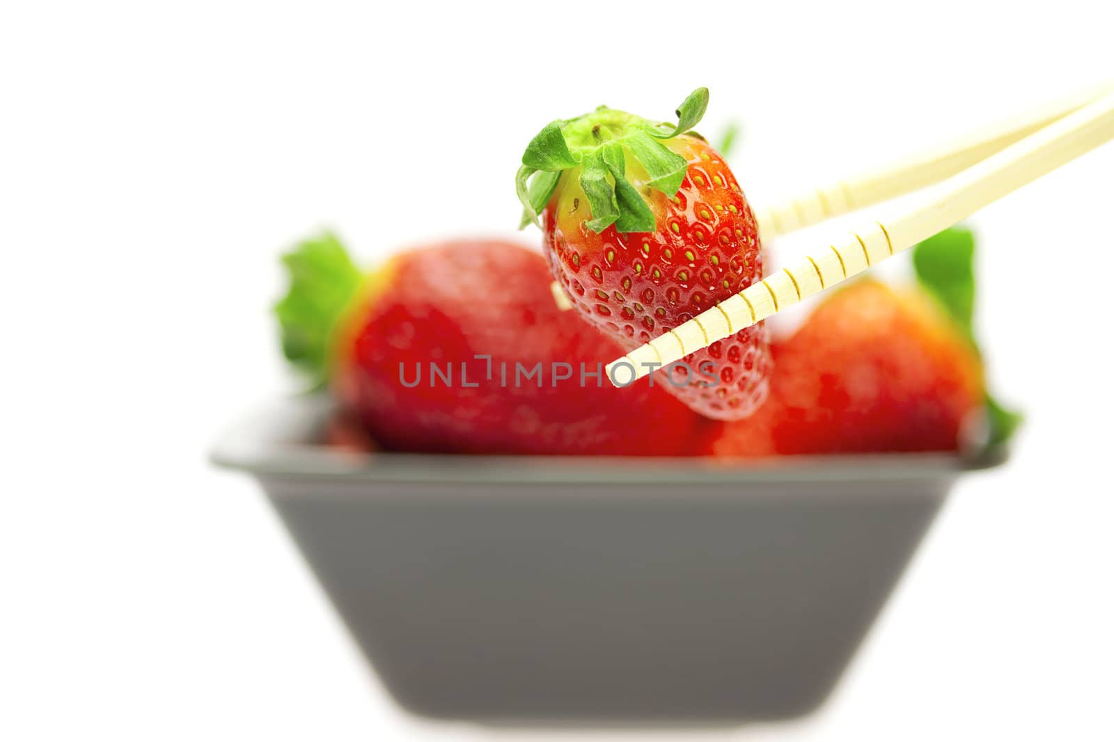 juicy strawberries in a bowl and Chinese chopsticks isolated on white