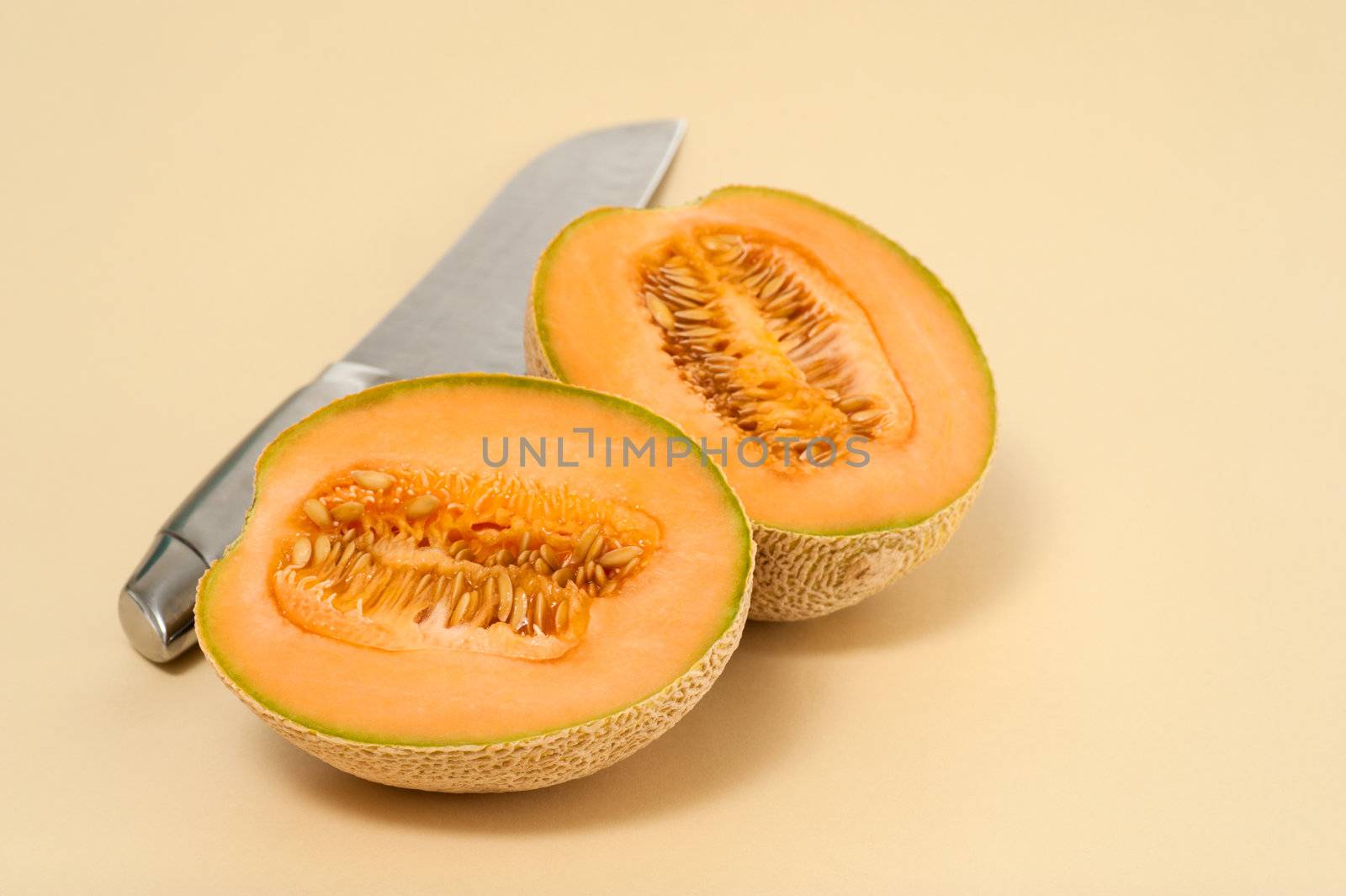 Cantaloupe cut in half on a neutral background.