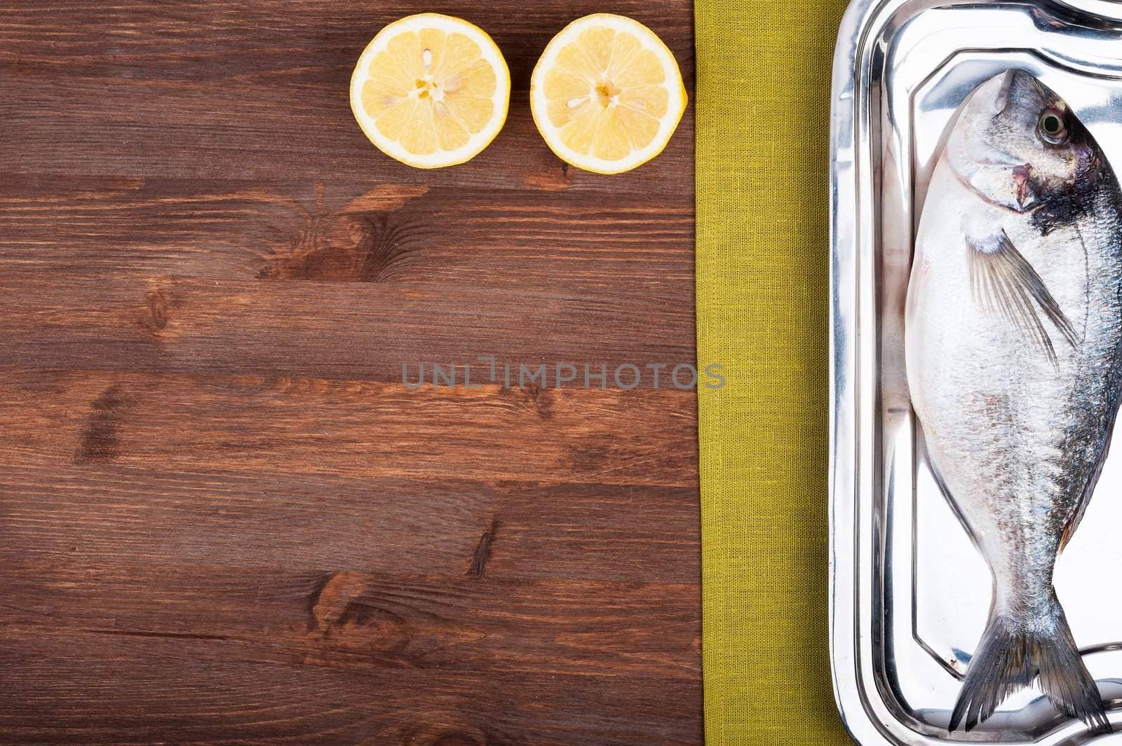 Dorado fish on a wooden surface with slices of lemon