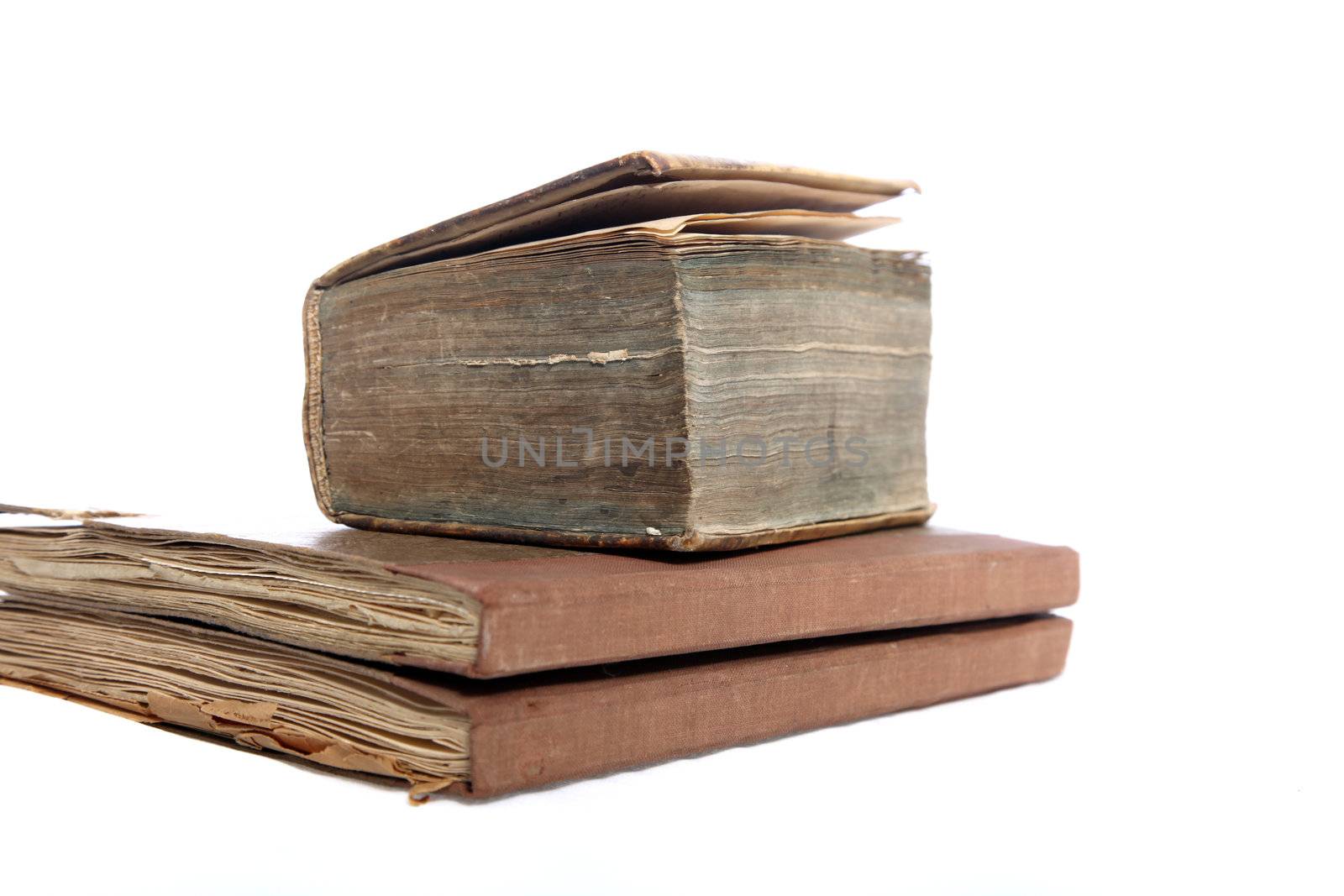 Three old vintage books with worn aged pages stacked on top of each other isolated on white