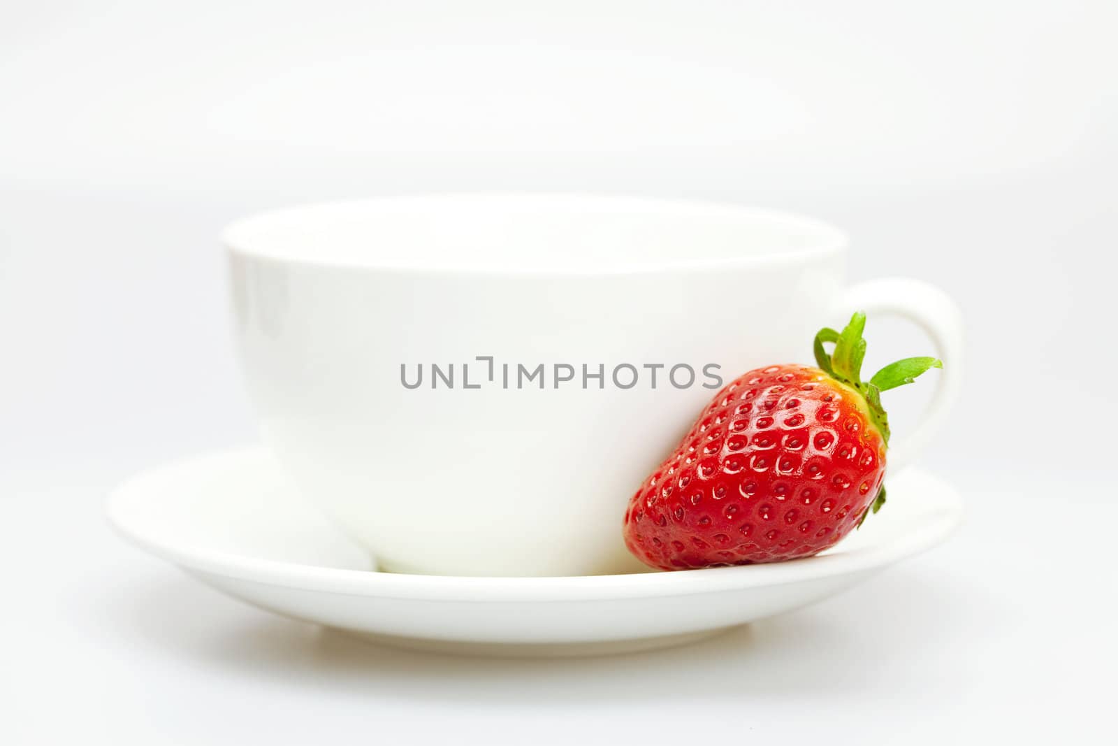 white cup and strawberries isolated on white by jannyjus