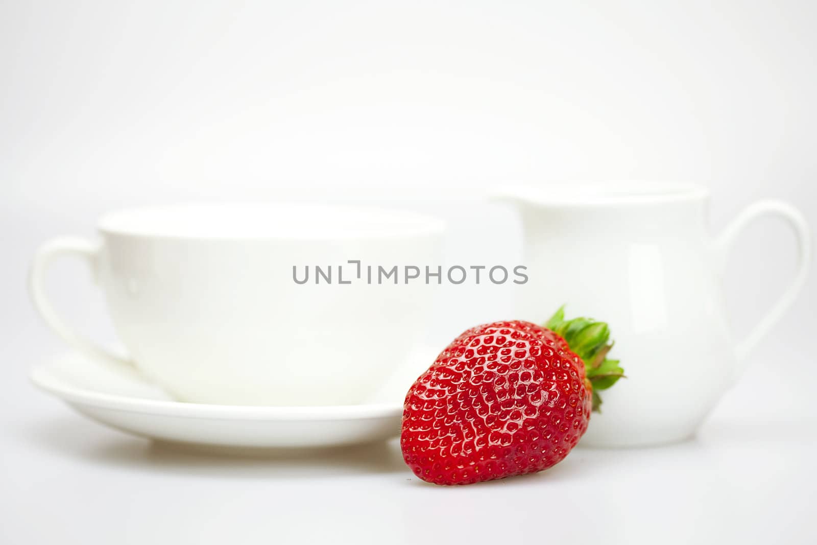 white cup and milk jug with strawberries isolated on white by jannyjus