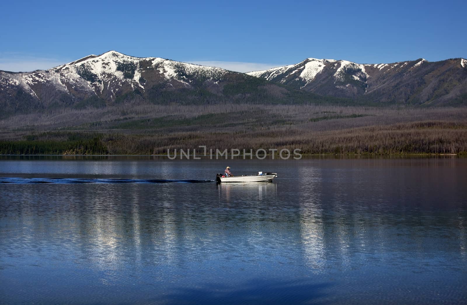 Lake McDonald Going Fishing Outboard in front of Snow Mountains Glacier National Park Montana