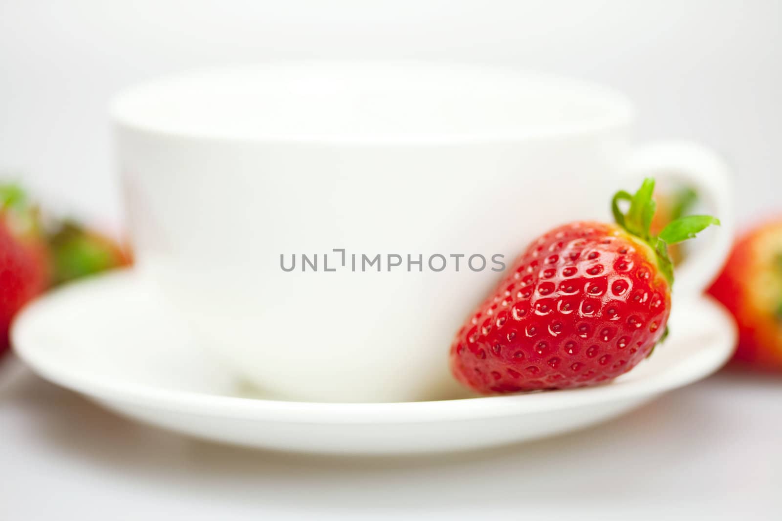 juicy strawberries and a cup of white isolated on white