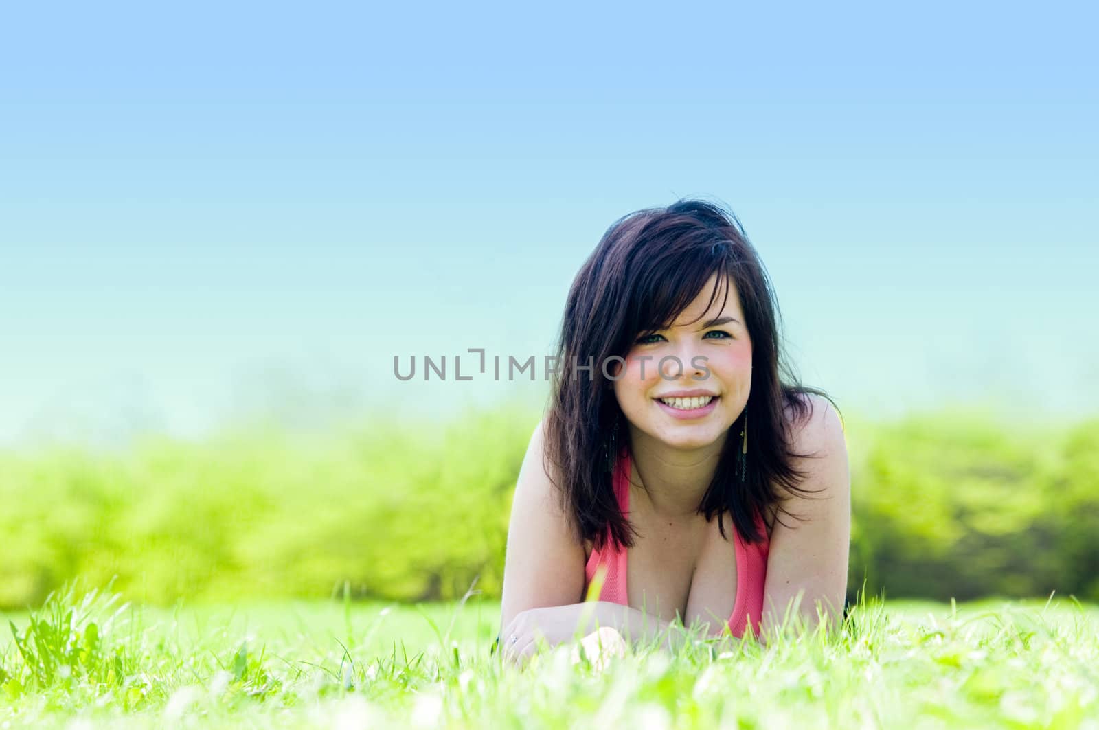 Young happy smiling girl lying on grass