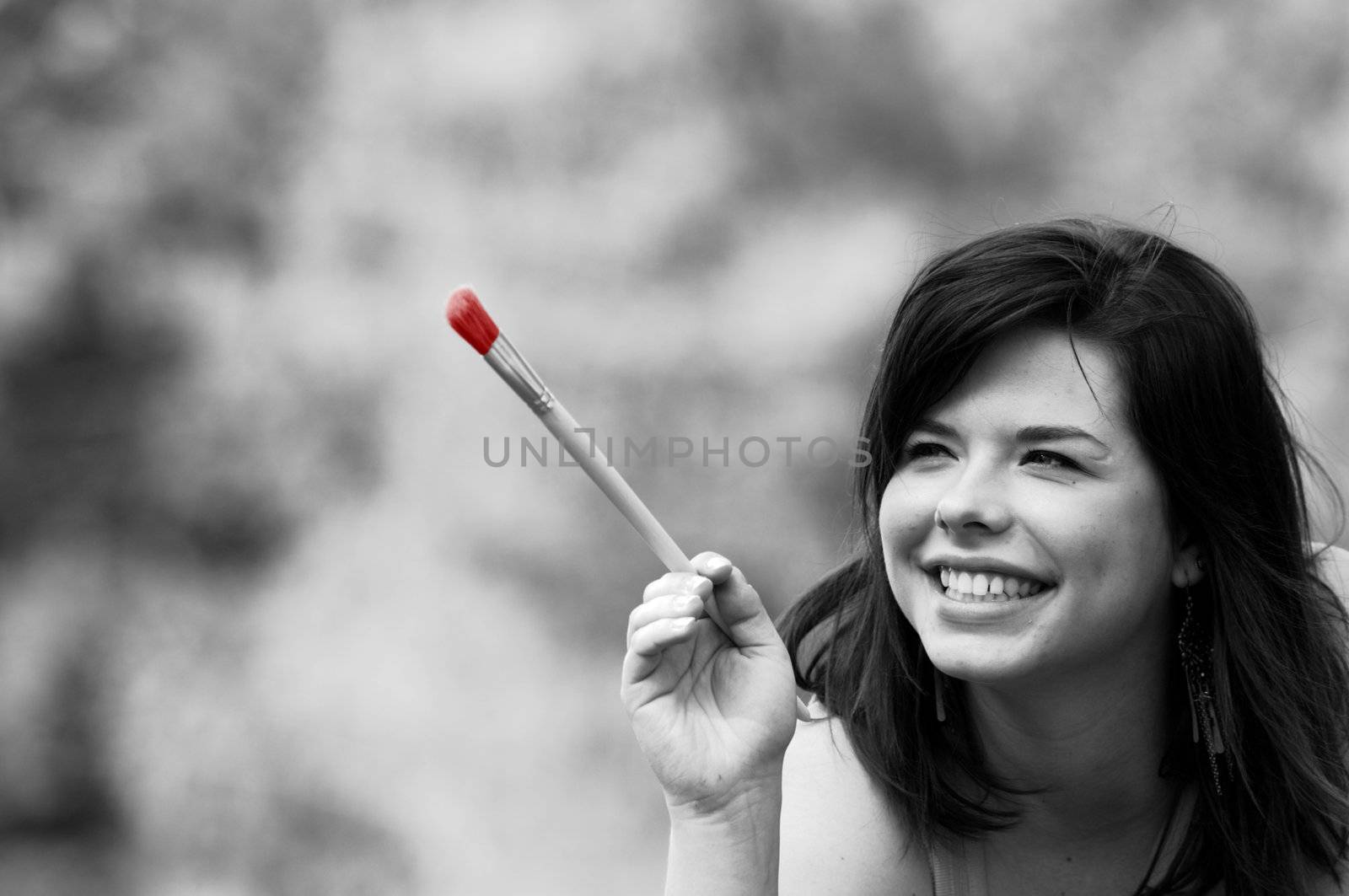 Painting the world. Smiling girl on grass with a paintbrush
