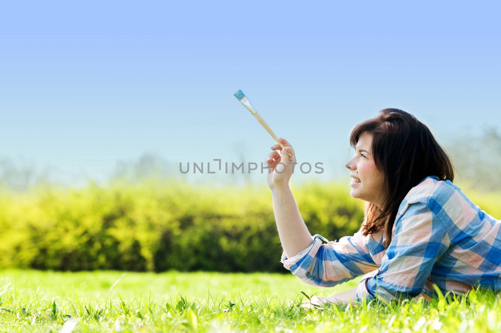 Painting the world. Smiling girl on grass with a paintbrush
