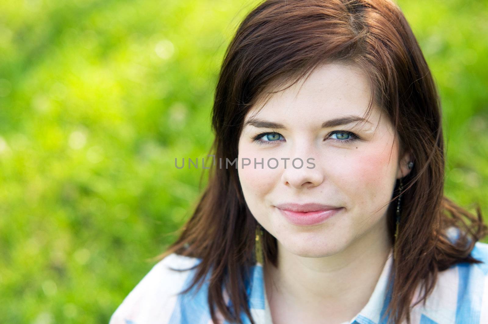Young happy girl portrait on grass, spring flowers background