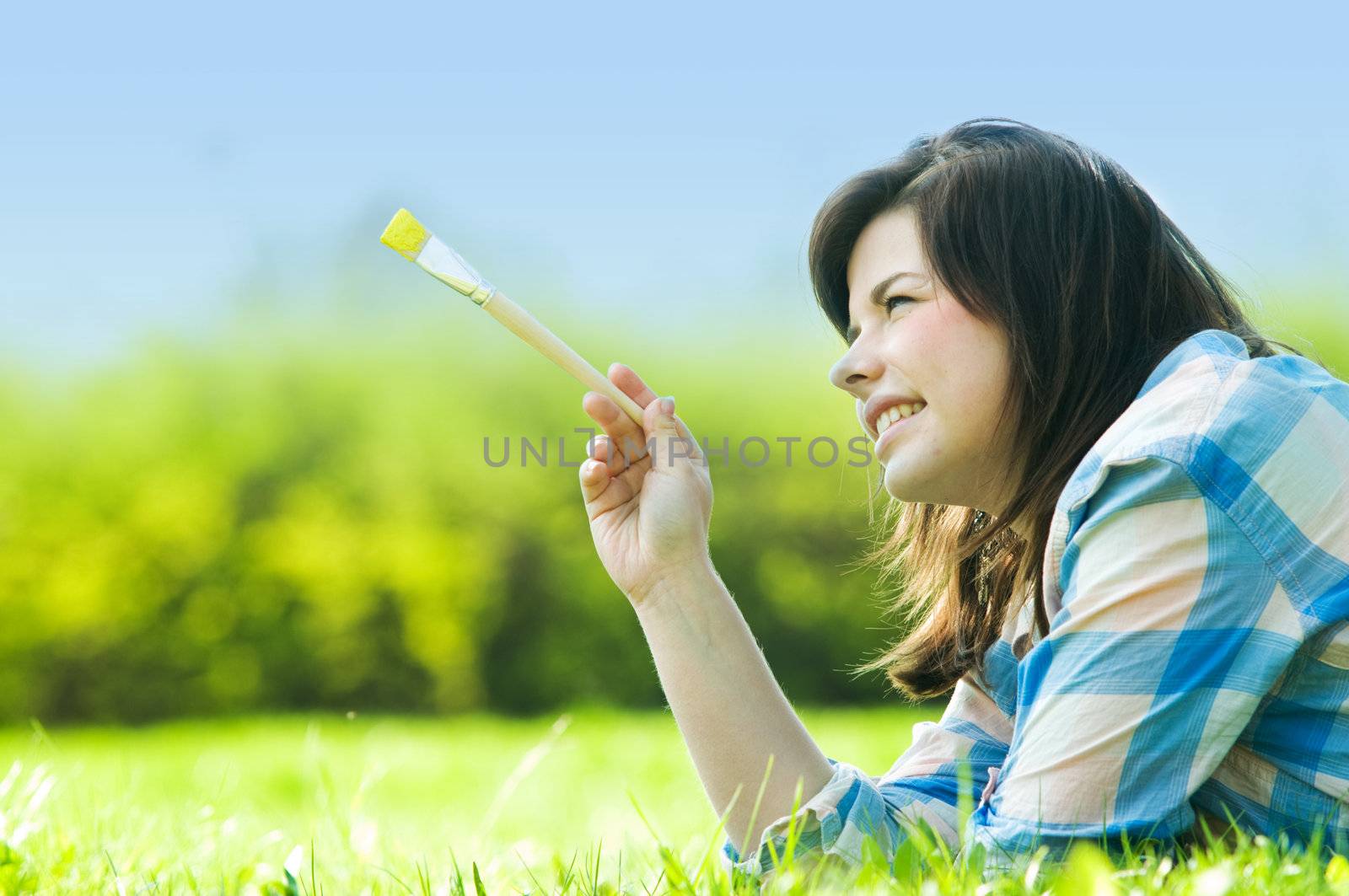 Painting the world. Smiling girl on grass with a paintbrush