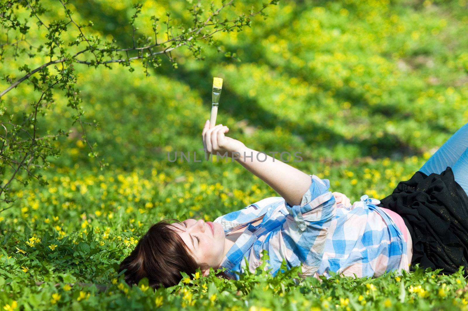 Painting the world. Smiling girl on grass with a paintbrush