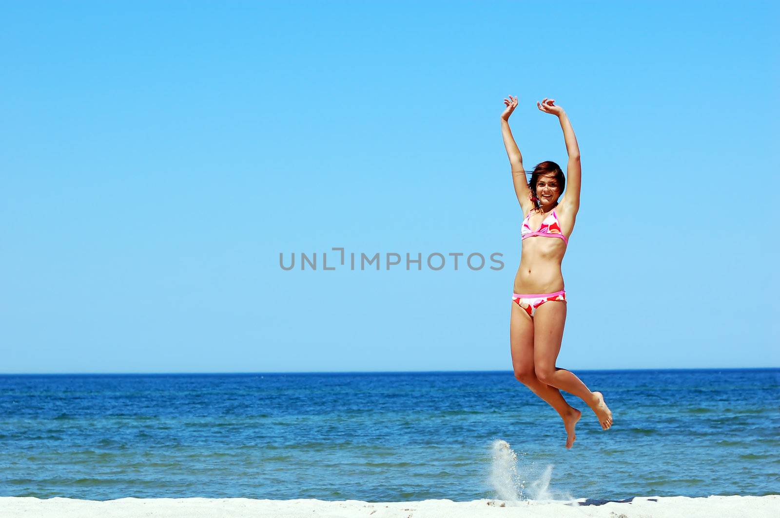 Young attractive woman jump on the beach