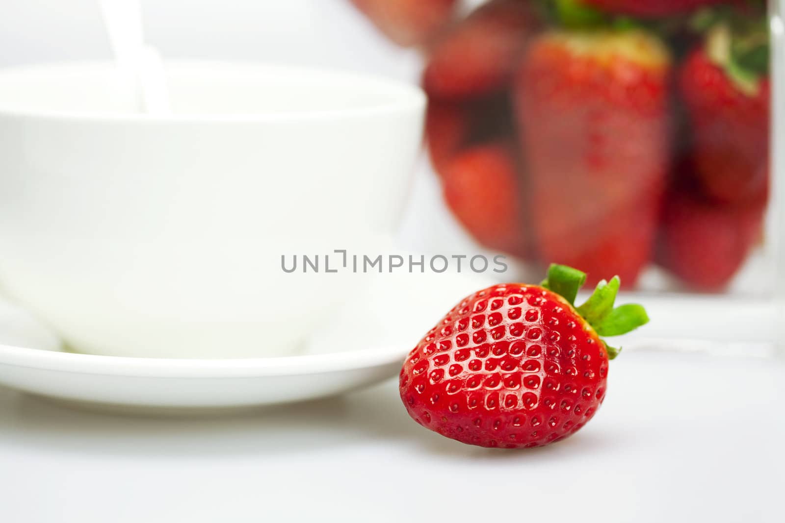 juicy strawberries and a cup of white isolated on white by jannyjus