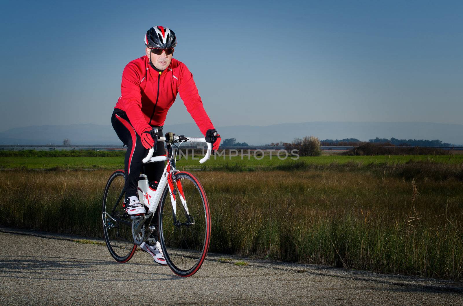 Man on road bike on open country road background.