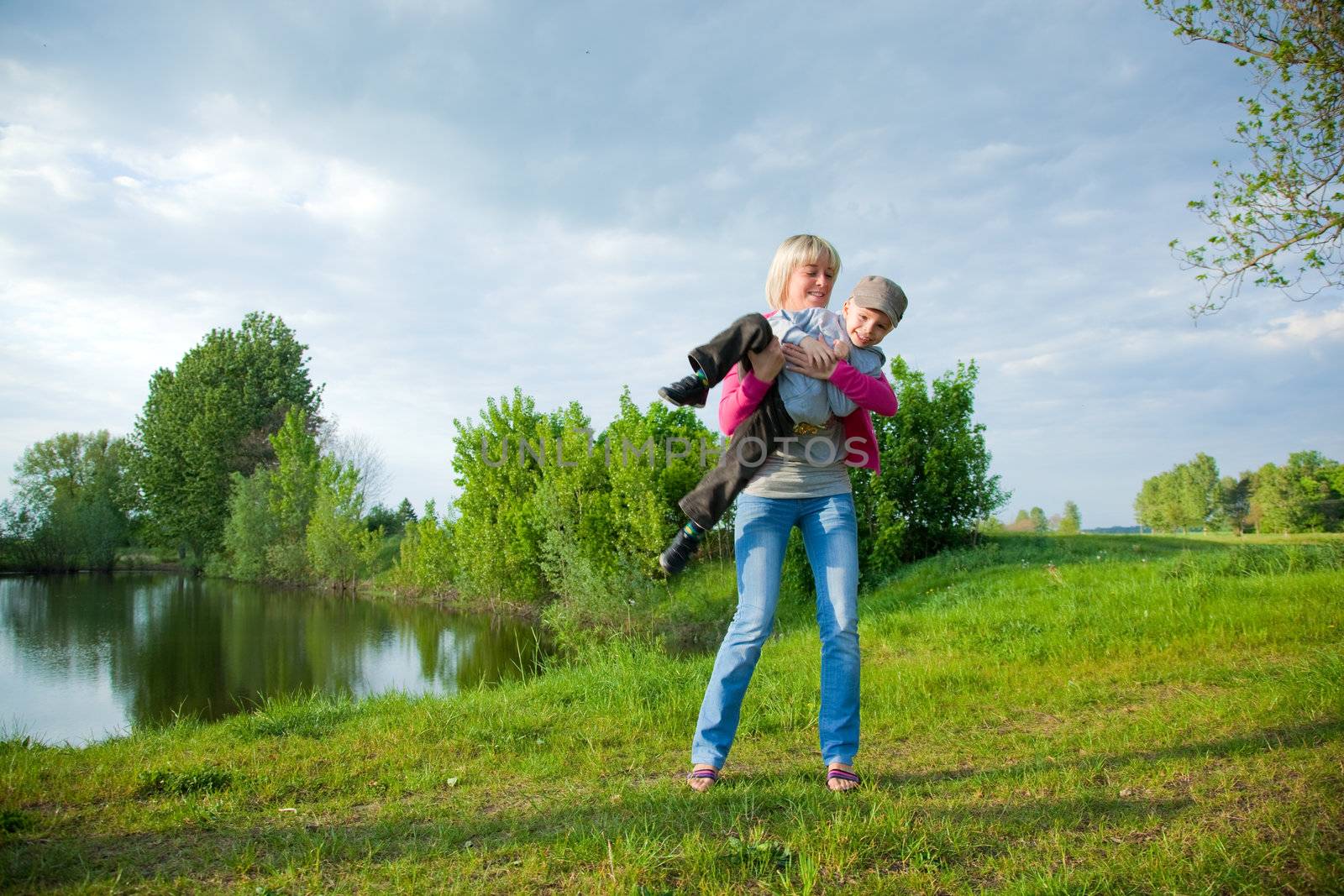 Young mother playing with her child outdooors in the summer