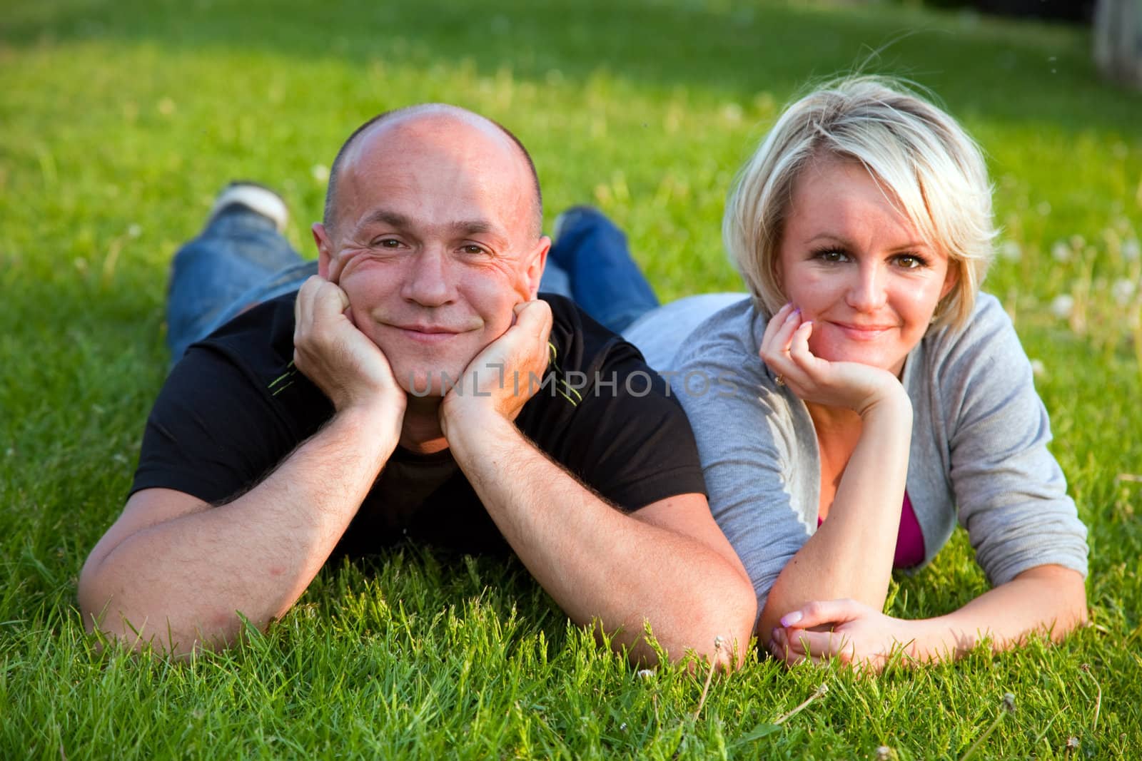 Adult happy couple together lying on grass