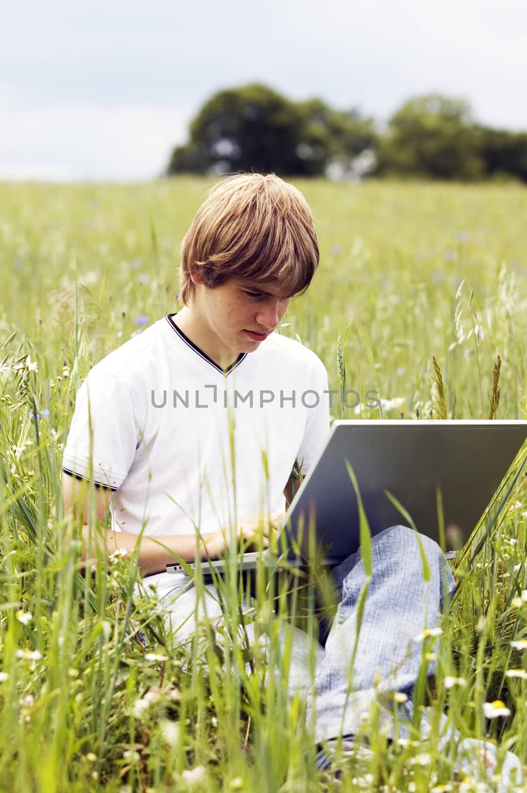 Boy using notebook outdoor on the field