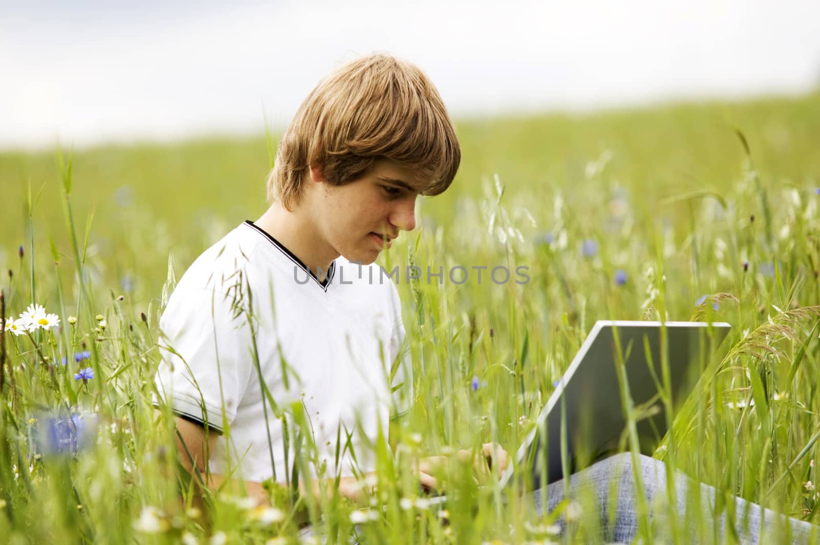 Boy using notebook outdoor on the field