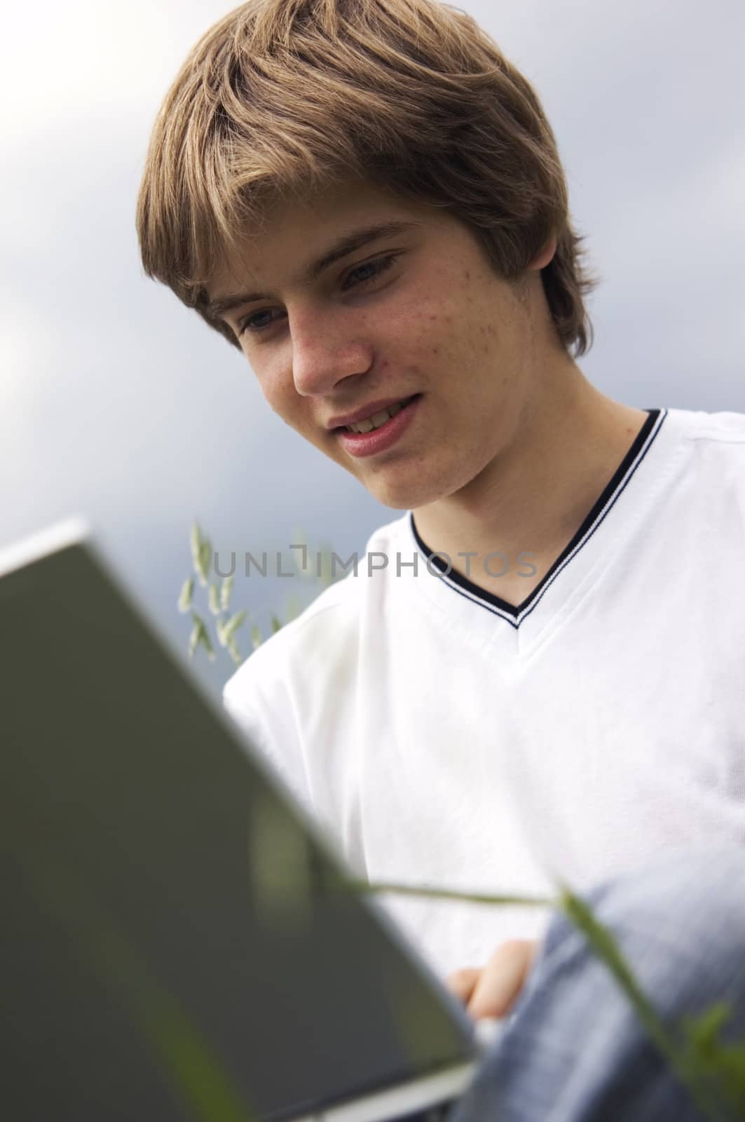 Boy using notebook outdoor on the field