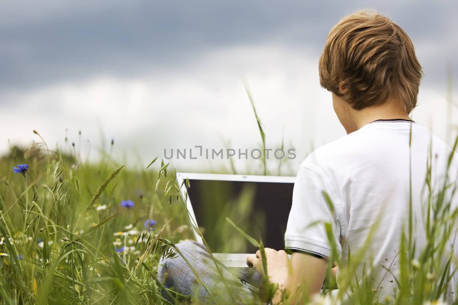 Boy using notebook outdoor on the field