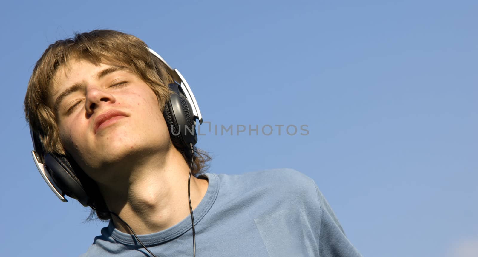 Boy listening to the music on blue bright sky 