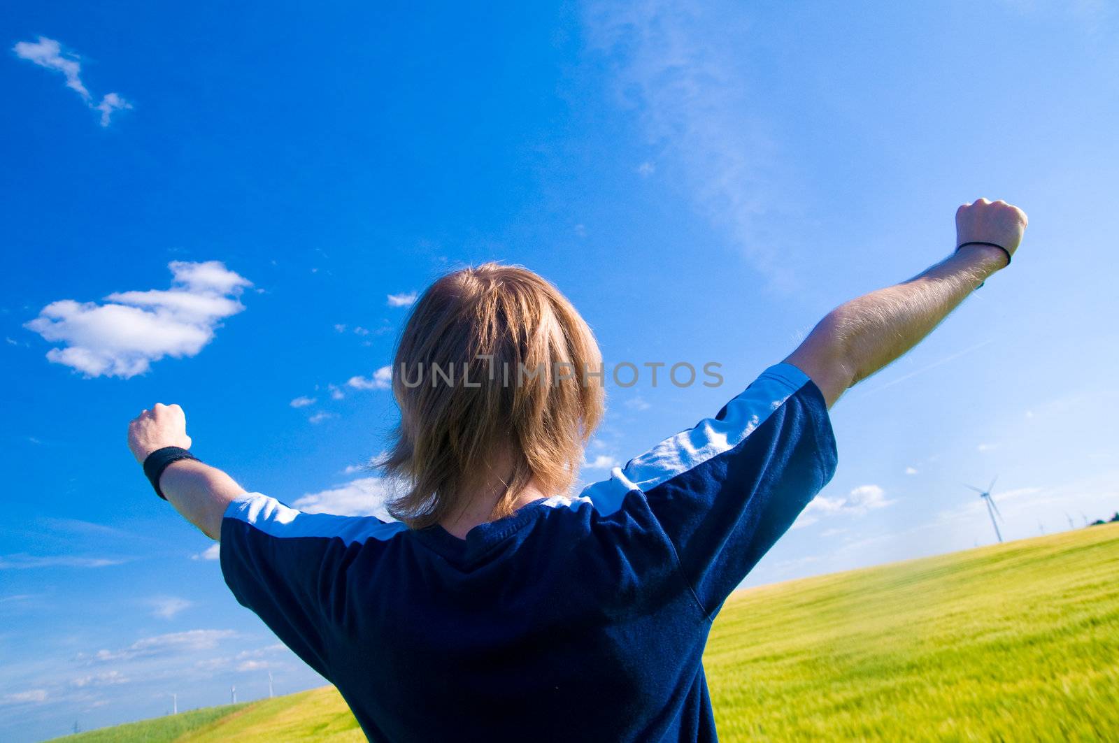 Happy man with arms up on summer landscape