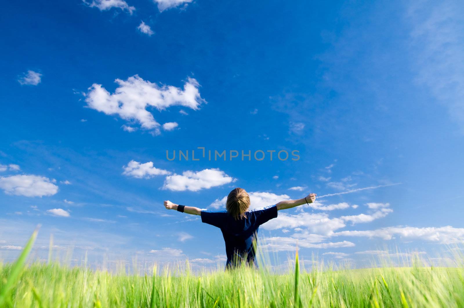 Happy man with arms up on summer field