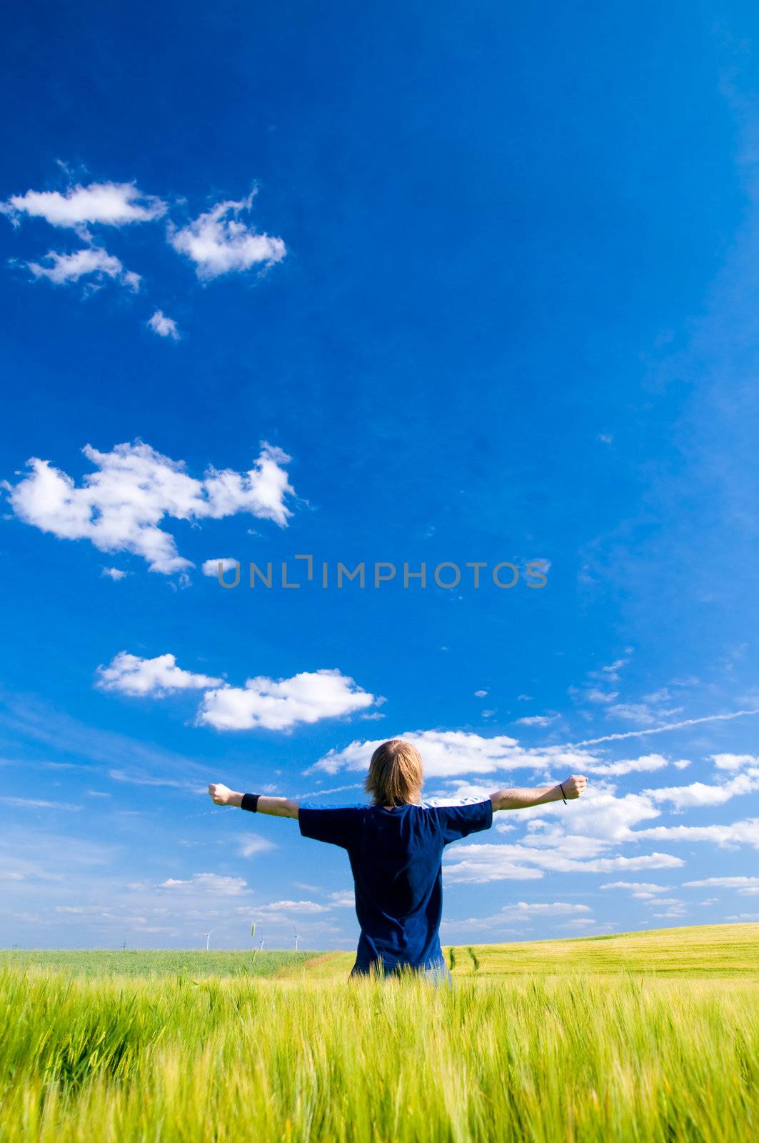 Happy man with arms up on summer lanscape