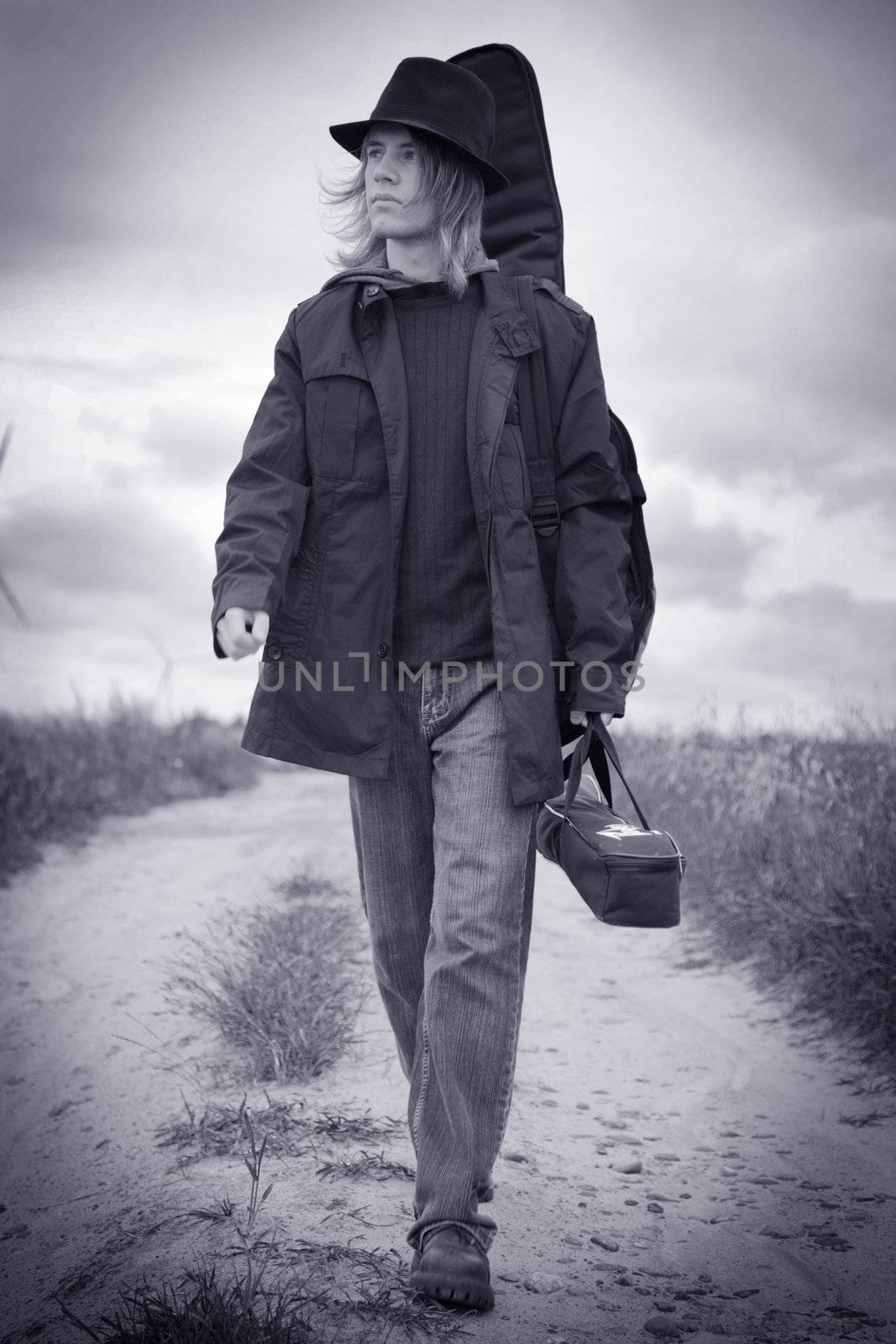 Full body portrait of a young musician walking on the field