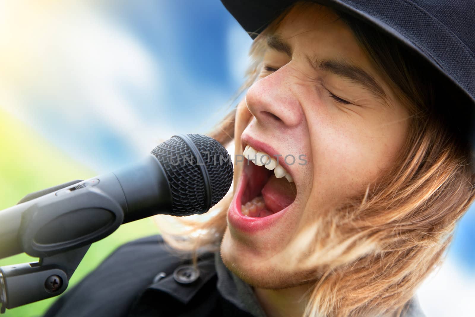 Young man in hat sings to microphone