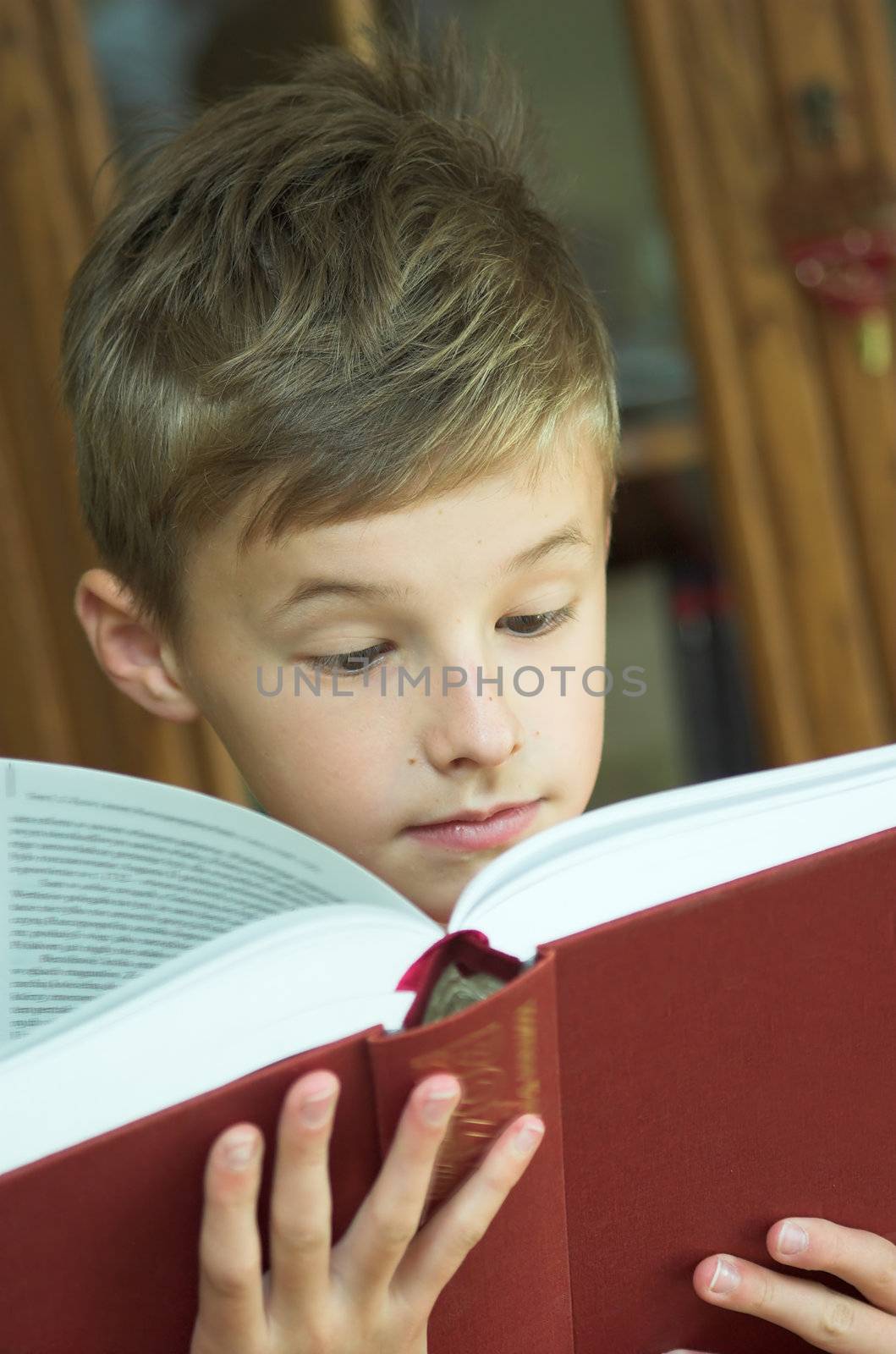 Young boy reading old, heavy book