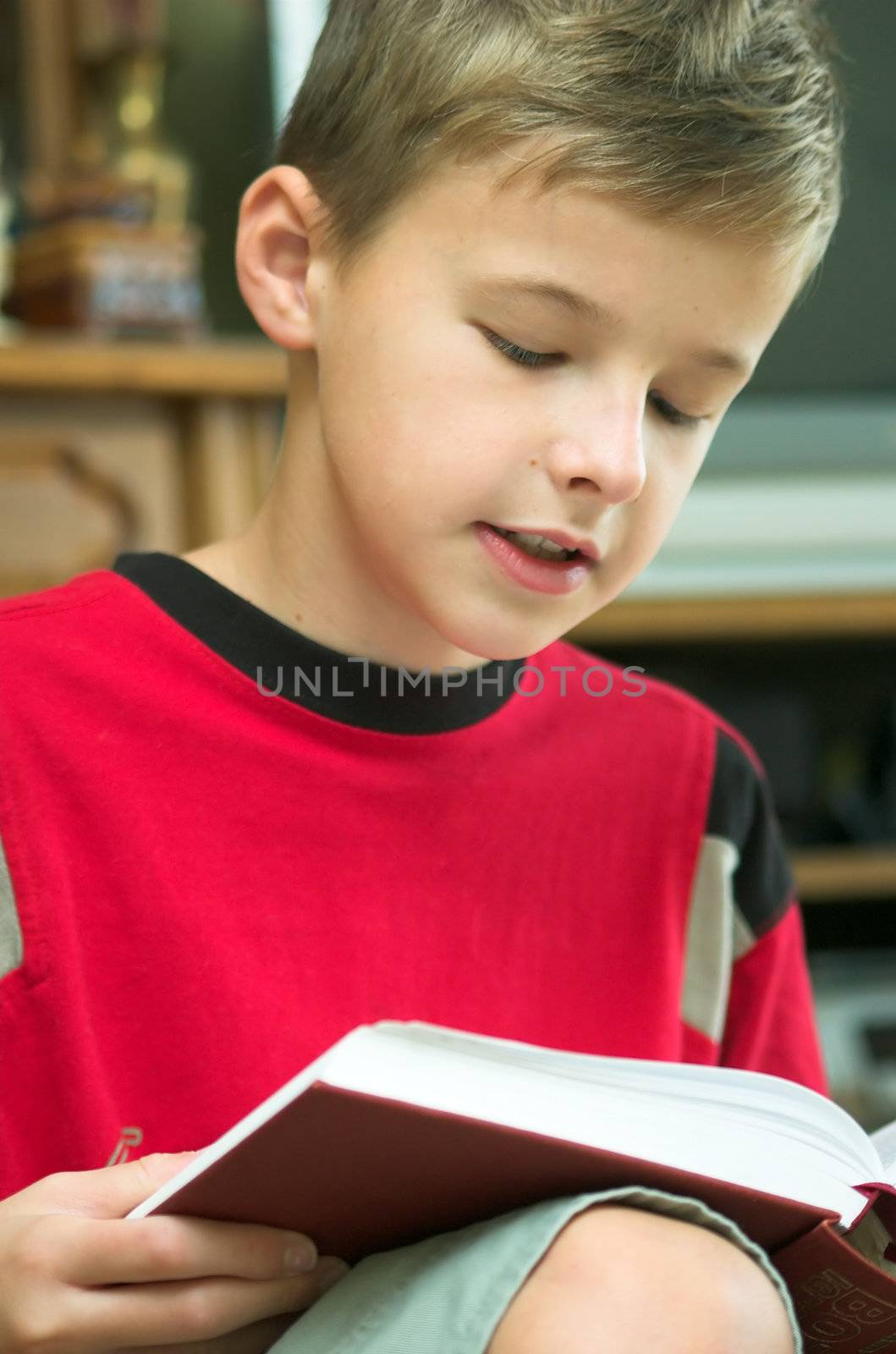 Young boy reading old, heavy book