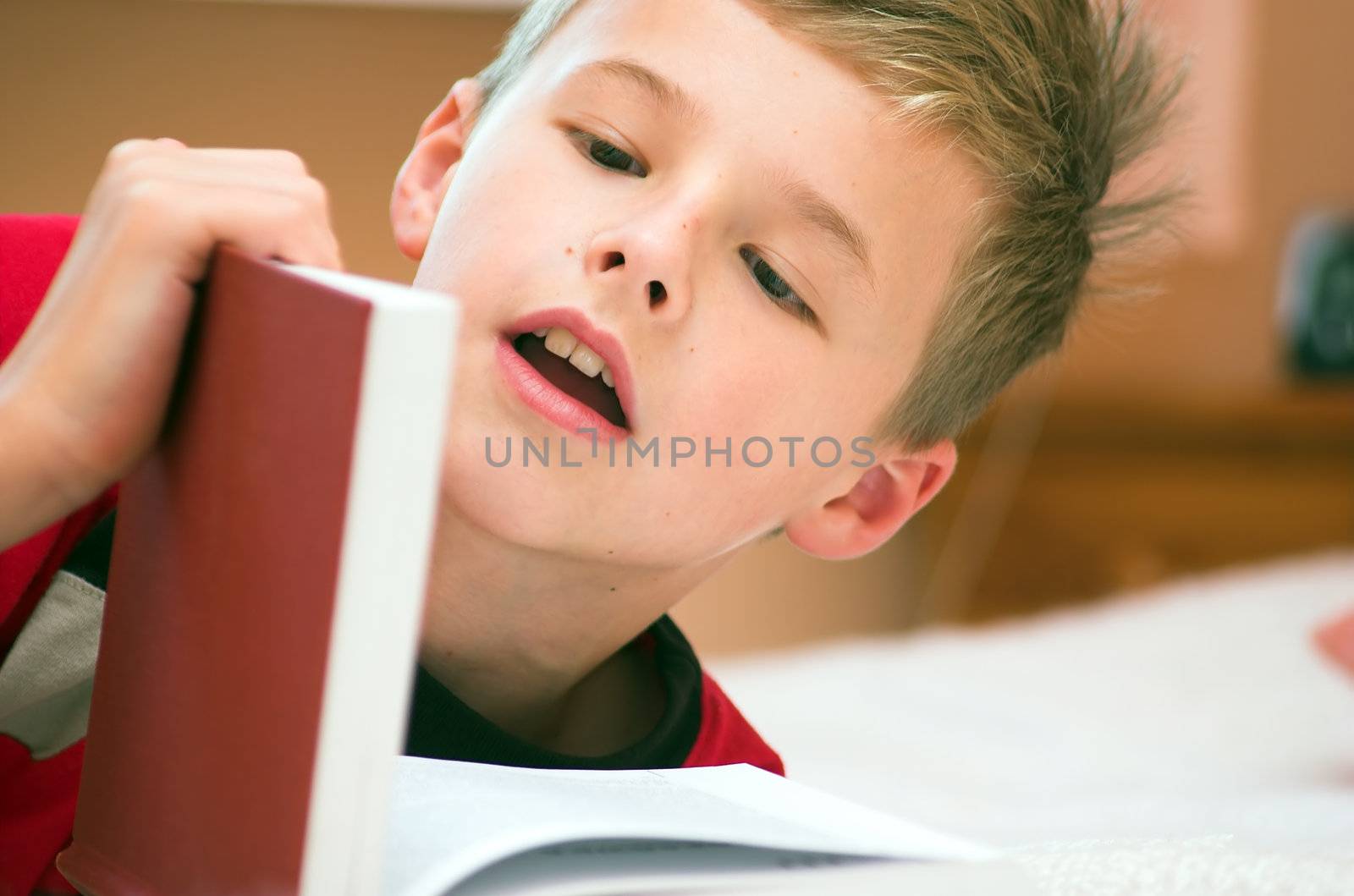 Young boy reading book on the bed 