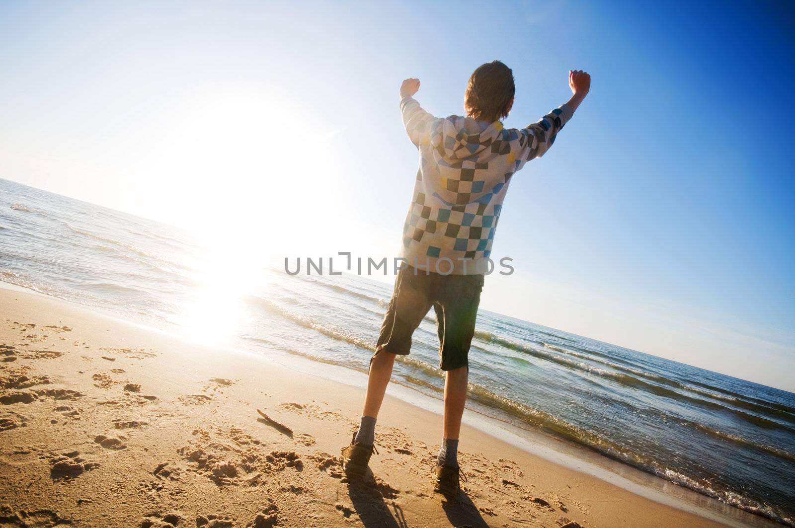 Happy boy jumping for joy at the beach