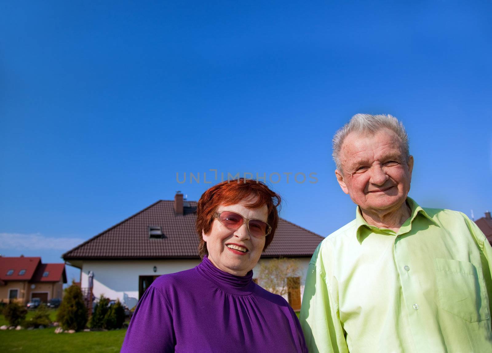 Senior smiling couple in front of their new house