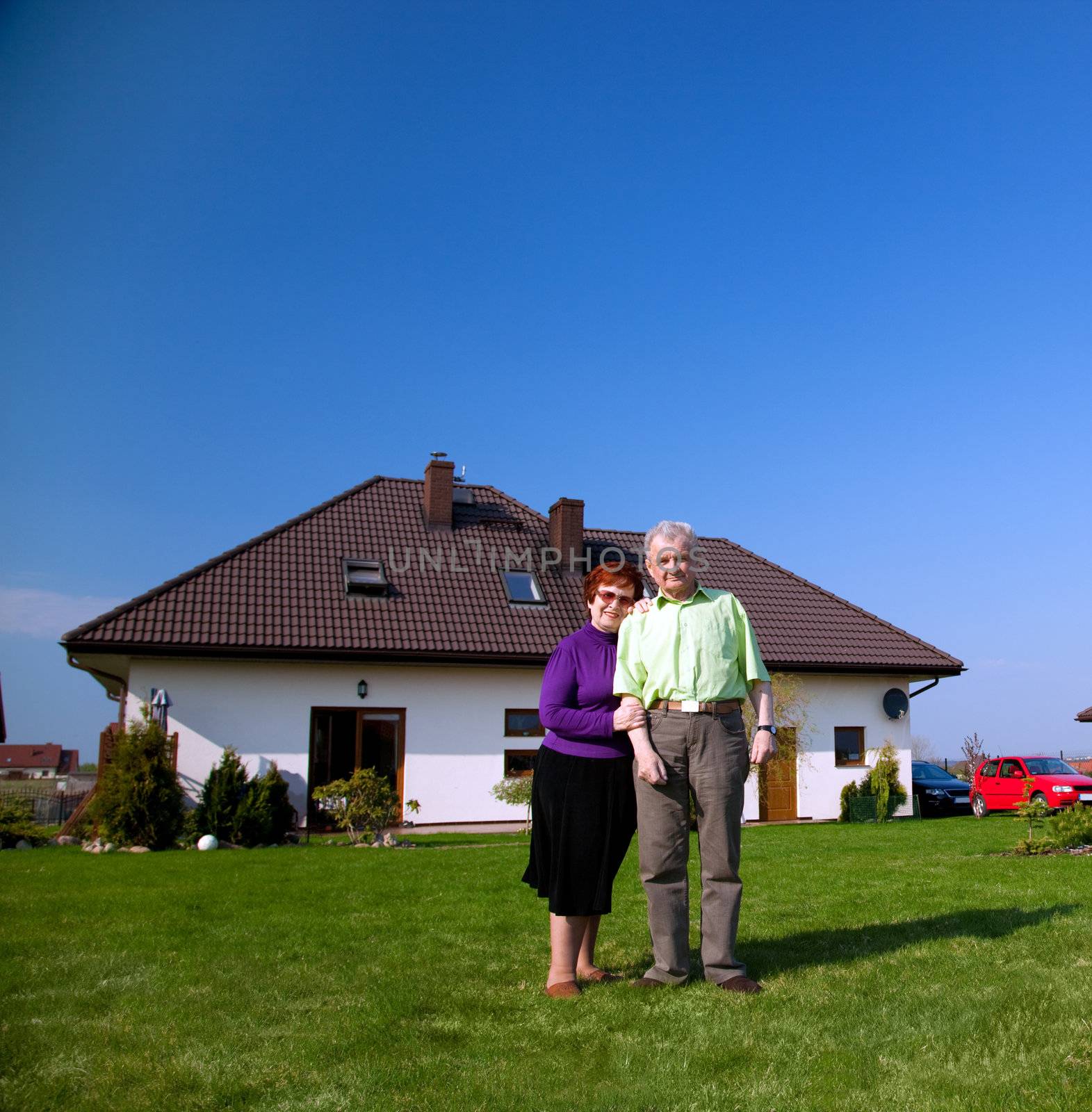 Senior smiling couple in front of their new house