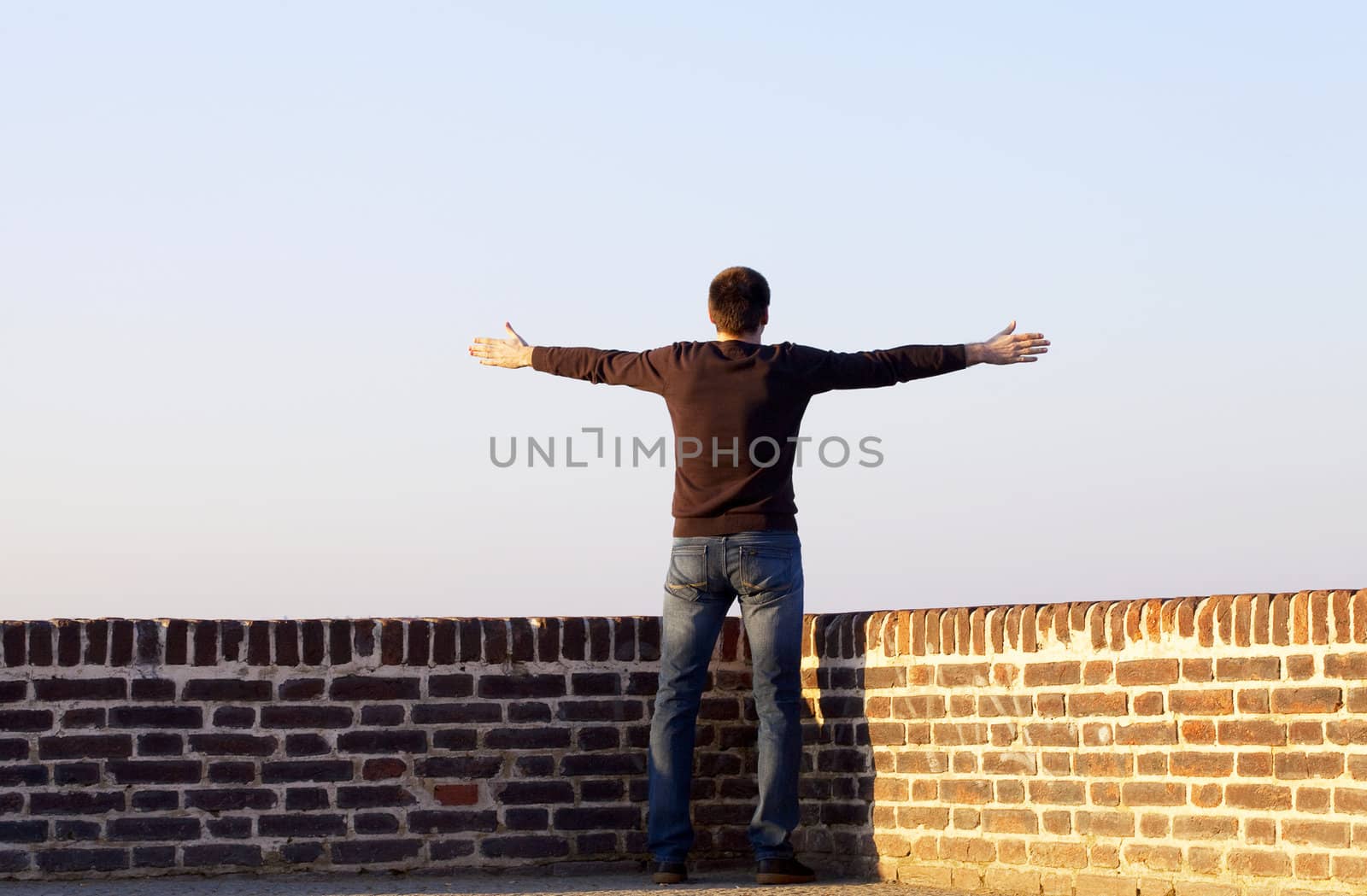 man with outstretched arms standing against the sky