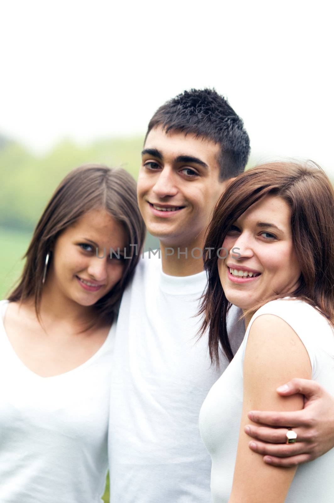 Three young happy friends standing together and smiling
