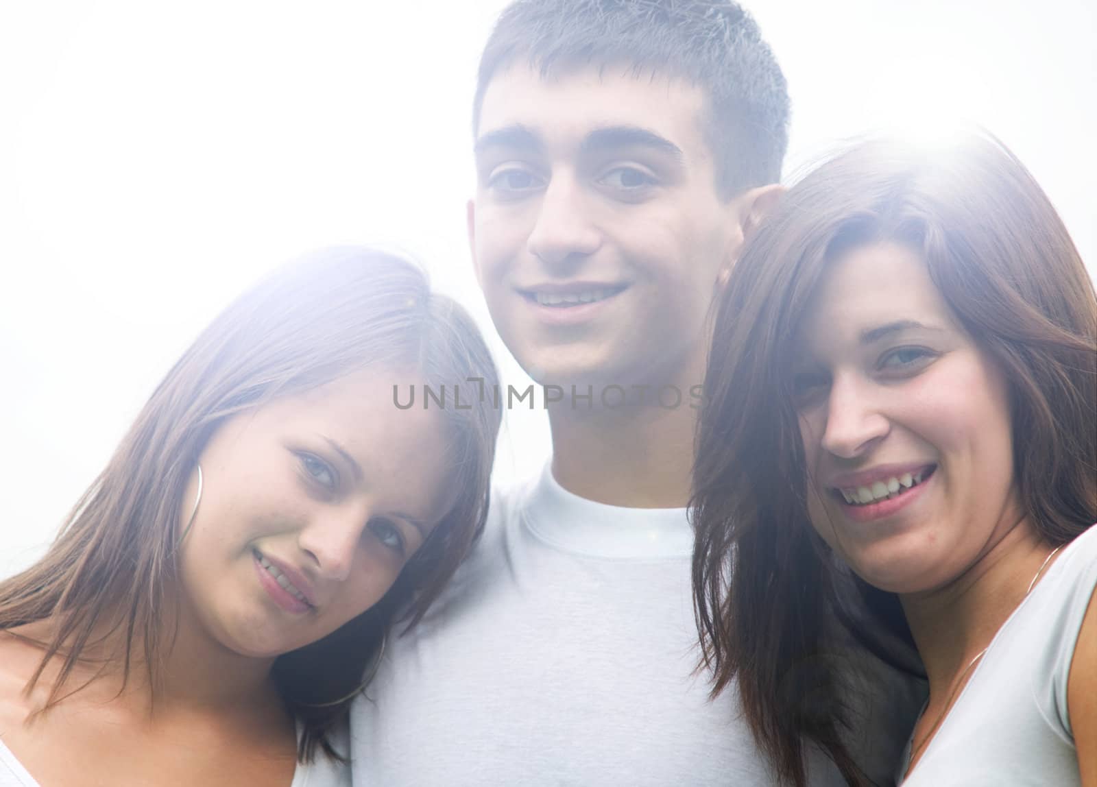 Low contrast shot of three young happy friends standing together and smiling