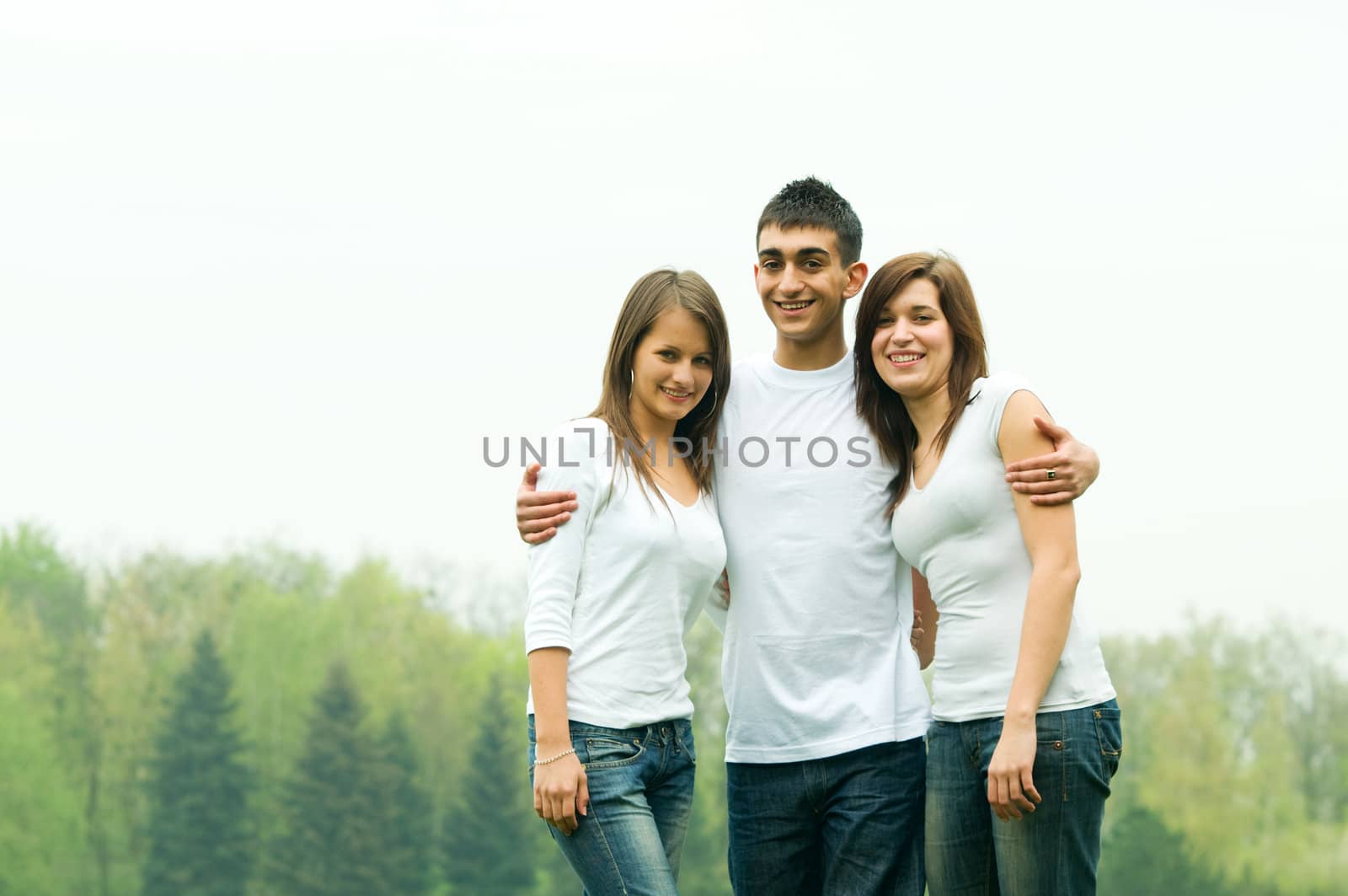 Three young happy friends standing together and smiling